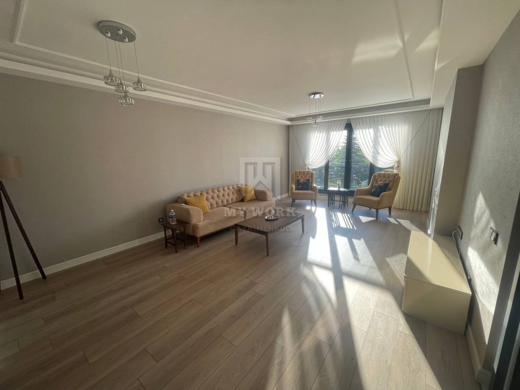 Koltuklar ve geniş cam kapı bulunan aydınlık salon